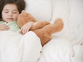Mixed race girl sleeping with teddy bear