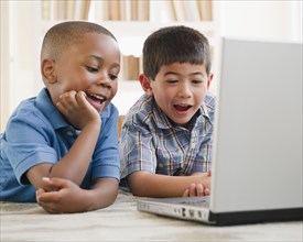 Smiling boys enjoying using a laptop