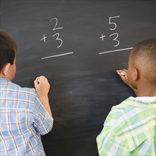 Boys solving math problems on blackboard