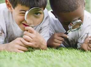 Boys looking at grass through magnifying glasses