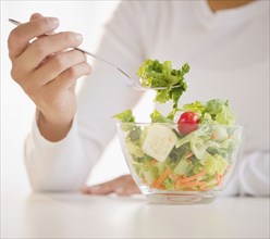 Mixed race woman eating salad