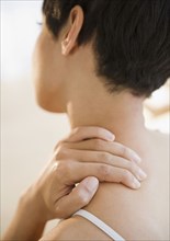 Mixed race woman rubbing neck and shoulder
