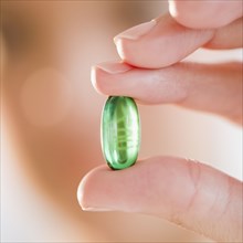 Hand holding green capsule