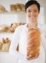 Mixed race woman in bakery holding bread