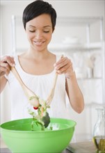 Mixed race woman mixing salad in kitchen
