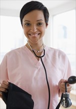 Mixed race doctor holding blood pressure gauge