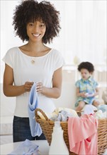 Mother folding laundry with daughter in background