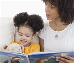 Woman reading book with daughter