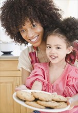 Mother and daughter holding plate of cookies