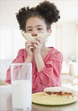 Mixed race girl holding sandwich in front of face