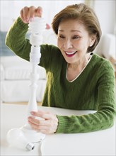 Japanese woman replacing energy efficient light bulb