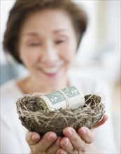 Japanese woman holding nest filled with money