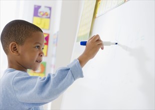 African American boy writing on white board