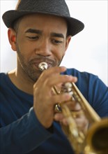 Mixed race man playing trumpet