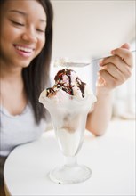 Smiling mixed race teenage girl eating ice cream sundae