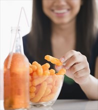 Close up of mixed race teenage girl eating cheese puffs