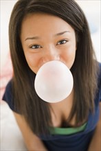 Close up of mixed race teenage girl blowing bubble with gum