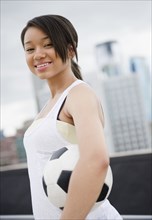 Smiling mixed race teenage girl holding soccer ball