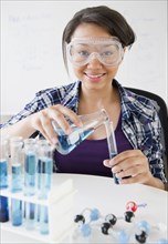 Smiling mixed race teenage girl conducting science experiment