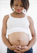 Smiling pregnant Black woman holding stomach