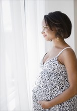 Smiling pregnant Black woman looking out window