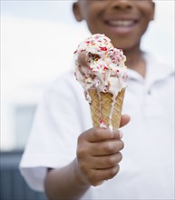 Close up of smiling Black boy holding melting ice cream cone
