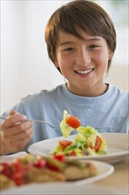 Smiling mixed race boy eating salad