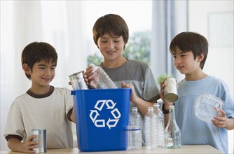 Mixed race brothers recycling plastic bottles and tin cans