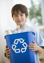 Smiling mixed race boy holding recycling bin