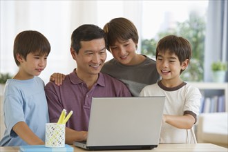 Smiling father and sons using laptop