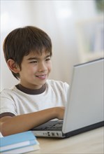 Smiling mixed race boy using laptop