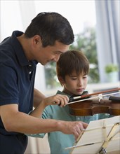 Father teaching son to play violin