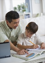 Father helping son with homework in living room