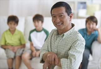 Smiling father in living room with sons in background