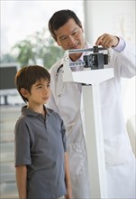Doctor weighing boy on scale