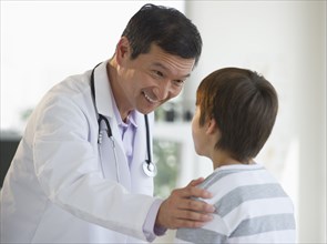 Smiling doctor touching boy's shoulder