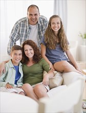 Smiling Hispanic family sitting on sofa together