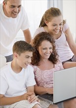 Smiling Hispanic family using laptop together
