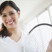 Smiling Hispanic woman holding tennis racquet