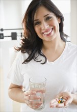 Smiling Hispanic woman taking vitamins