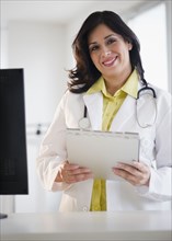 Smiling Hispanic doctor holding medical record