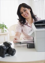 Smiling Hispanic woman using printer