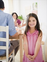 Smiling girl with family at dinner table behind her