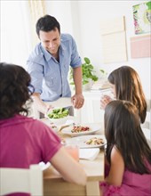 Father bringing salad to table for family dinner