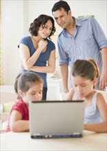 Father and mother watching children using internet together