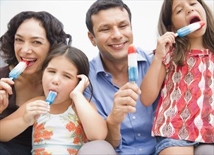 Smiling family eating popsicles together