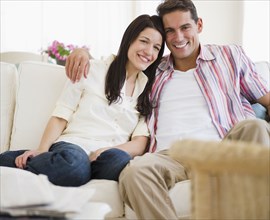 Smiling couple sitting on sofa together