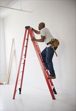 African American construction worker climbing ladder