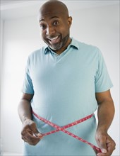 Happy African American man measuring his waistline