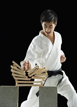 Asian male karate black belt breaking wooden planks